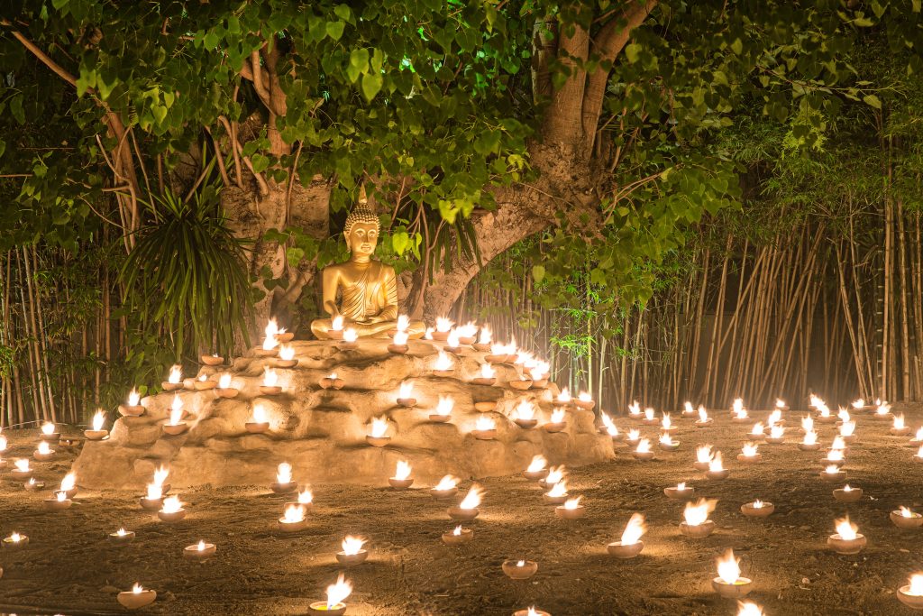 Buddhist monk fire candles to the Buddha with beautiful water reflection in Phan Tao Temple, Chiangmai, Thailand